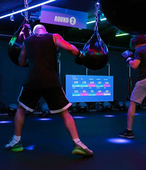 Man performing a strength exercise in a modern, dark gym setting.